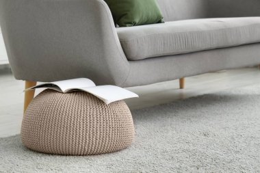 Yumuşak örülmüş puf dergi ve oturma odasında rahat gri kanepe, yakın çekim.