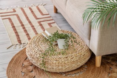 Havalı hasır puf çiçekli ve oturma odasında rahat bir kanepe.