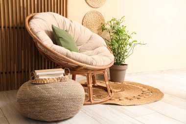 Rahat koltuğu ve bej duvarın yanındaki ahşap perdesi olan şık hasır pouf.