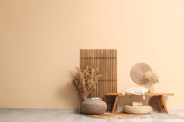 Hasır puflar ahşap banklar ve oda bej duvarın yanında katlanır ekran