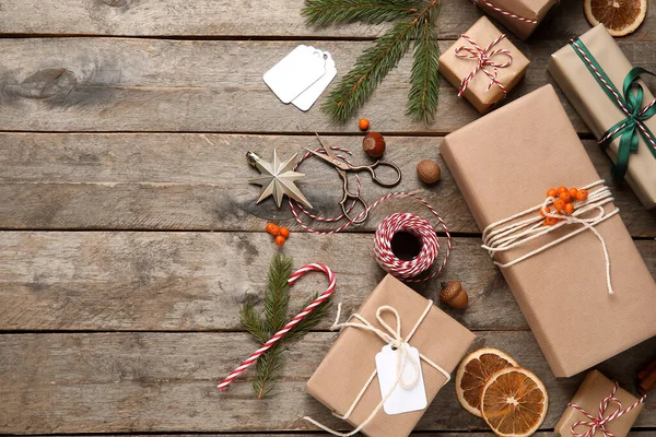 İp, makas, köknar ağacı dalları ve ahşap arka planda yabanmersini dolu Noel hediyesi kutuları.