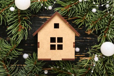 Siyah ahşap arka planda dekoratif evi olan Noel çelengi.