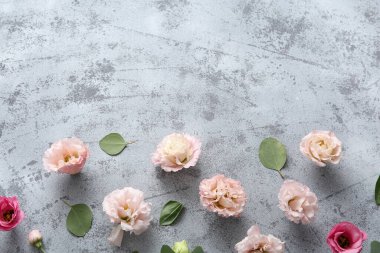 Composition with beautiful eustoma flowers and leaves on grey grunge background
