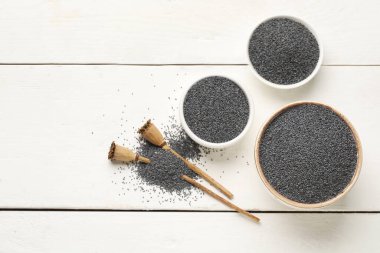 Beyaz ahşap arka planda haşhaş tohumlu kaseler