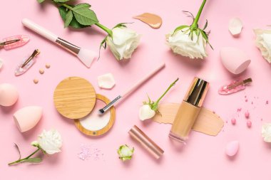 Composition with white rose flowers, makeup products and brushes on pink background