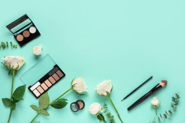 Beyaz gül çiçekleri, makyaj ürünleri ve nane arkaplanda fırçalar olan kompozisyon