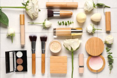 Beyaz gül çiçekli kompozisyon, makyaj ürünleri ve bej fayanslı fırçalar