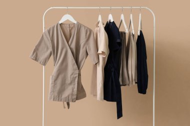 Rack with massage therapist's uniform on beige background