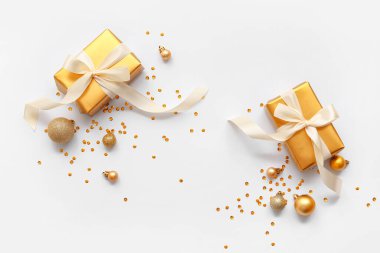 Composition with golden Christmas balls, confetti and gift boxes on white background