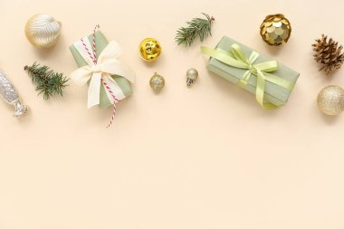 Altın Noel topları, hediye kutuları ve bej arka planda köknar ağacı dalları olan kompozisyon