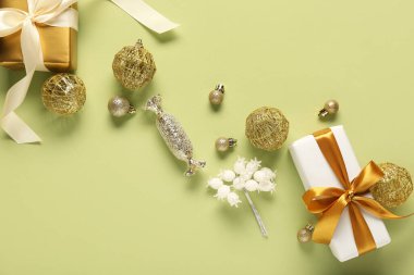 Altın Noel topları ve yeşil arka planda hediye kutuları olan kompozisyon