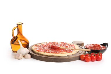 Ham hamurlu ahşap tahta ve beyaz arka planda pizza malzemeleri.