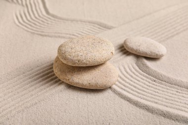 Arka plan olarak kumun üzerindeki kaplıca taşları ve çizgilerle kompozisyon, yakın plan. Zen kavramı