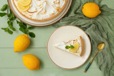 Plate with piece of tasty lemon pie on green wooden table