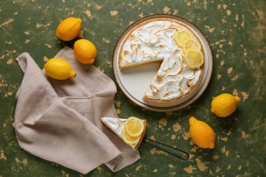 Plate with tasty lemon pie on green grunge background