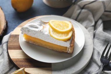 Plate with piece of tasty lemon pie on blue grunge background, closeup