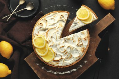 Plate with tasty lemon pie on black grunge background, closeup