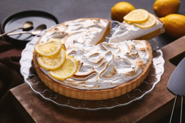 Plate with tasty lemon pie on black grunge background, closeup