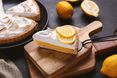 Spatula with piece of tasty lemon pie on black grunge background, closeup