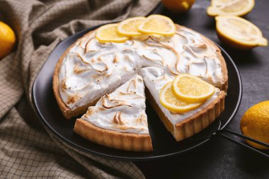 Plate with tasty lemon pie on black grunge background, closeup