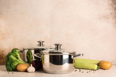 Cooking pots with different vegetables on light background
