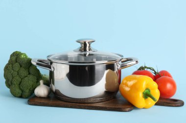 Mavi arka planda farklı sebzelerle pişirme kabı