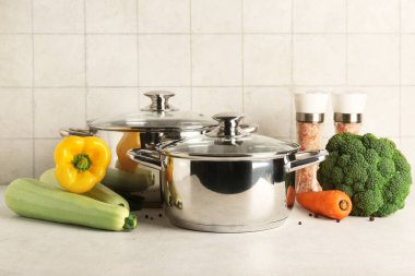 Farklı sebzelerle tencereler ve hafif arka planda biberler.