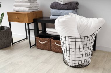 Coffee tables with baskets and bed sheets near white wall in living room