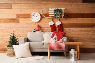 Gri kanepesi, kızağı, Noel süsü ve saati olan şenlikli bir oturma odası.