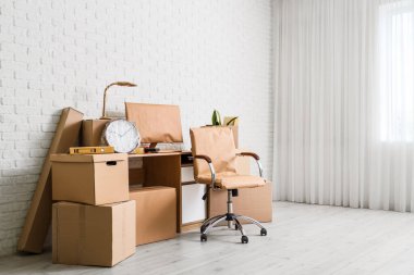 Ofiste beyaz tuğla duvarın yanında kutuları taşıyan sandalye.