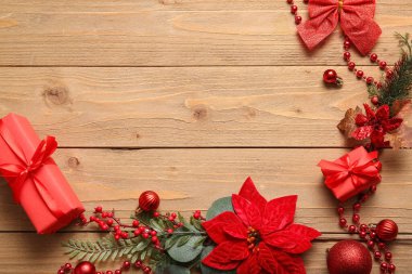 Noel çiçeğinden yapılmış çerçeve ve tahta arka planda hediye kutuları