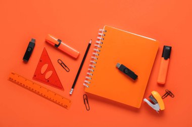 Turuncu arkaplanda defter, kırtasiye ve modern flaş bellek kompozisyonu