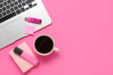 Dizüstü bilgisayarlı kompozisyon, bir fincan kahve, kırtasiye malzemesi ve pembe arka planda modern flash bellek.