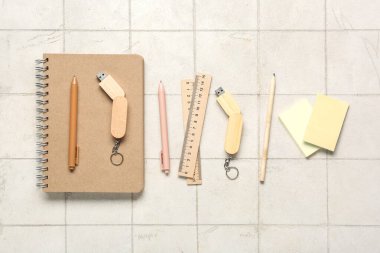 Beyaz kartonlu arkaplan üzerinde not defterleri, kırtasiye ve modern flaş sürücüleri olan kompozisyon