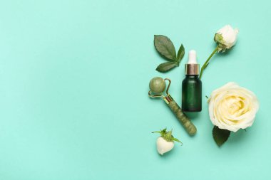 Turkuaz arka planda yeşil silindirli güzel beyaz gül çiçekleri ve bir şişe kozmetik yağ