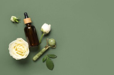 Beautiful white rose flowers with bottle of cosmetic oil and jade roller on green background