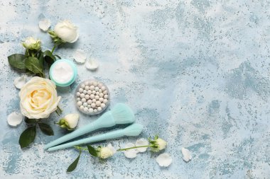 Mavi grunge arka planda beyaz gül çiçekleri, makyaj fırçaları ve kozmetik ürün kavanozu ile kompozisyon