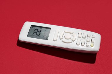 Kırmızı arkaplanda klima uzaktan kumandası, yakın plan.