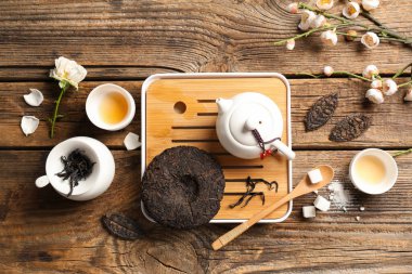 Kuru ütülenmiş çay tepsisi, çaydanlık, fincanlar ve kiraz çiçeği ahşap arka planda.