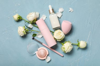 Beyaz gül çiçekleri, kozmetik ürünleri şişeleri ve mavi grunge arka planda makyaj süngeri olan kompozisyon