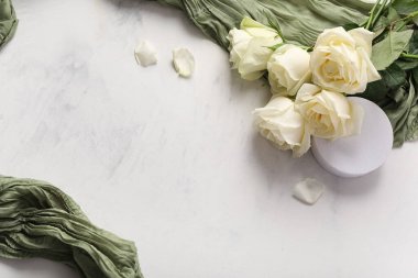 Alçıdan podyumlu güzel gül çiçekleri ve açık arkaplanda yeşil kumaş