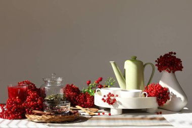 Çaydanlık ve bir fincan sıcak viburnum çayı oturma odasındaki beyaz duvarın yanındaki masada.