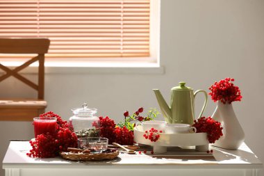 Çaydanlık ve bir fincan sıcak viburnum çayı oturma odasının penceresinin yanındaki masada.