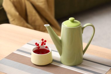 Çaydanlık ve bir fincan sıcak viburnum çayı oturma odasındaki masada, yakın plan.