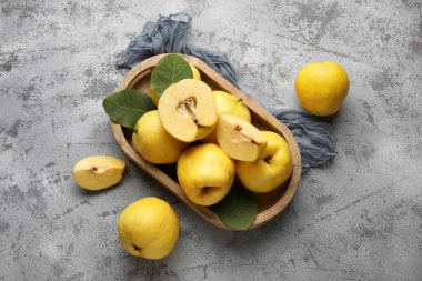 Tahta tepsi, tatlı olgun ayva ve gri arka planda yapraklar.