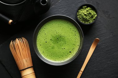 Siyah grunge arkaplanda bir kase kibrit çayıyla kompozisyon, yakın plan.