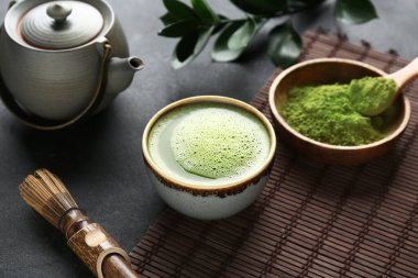 Siyah grunge arkaplanda bir kase kibrit çayıyla kompozisyon, yakın plan.