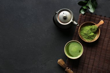 Siyah grunge arkaplanda bir kase kibrit çayı ile kompozisyon