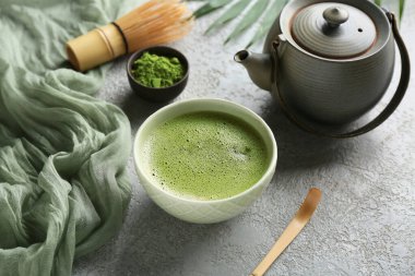 Gri grunge arka planda bir kase kibrit çayı ve çaydanlık ile kompozisyon, yakın plan.