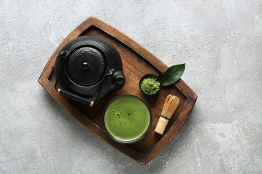 Ahşap tepside bir kase kibrit çayı, çaydanlık ve gri grunge arka planda chasen.